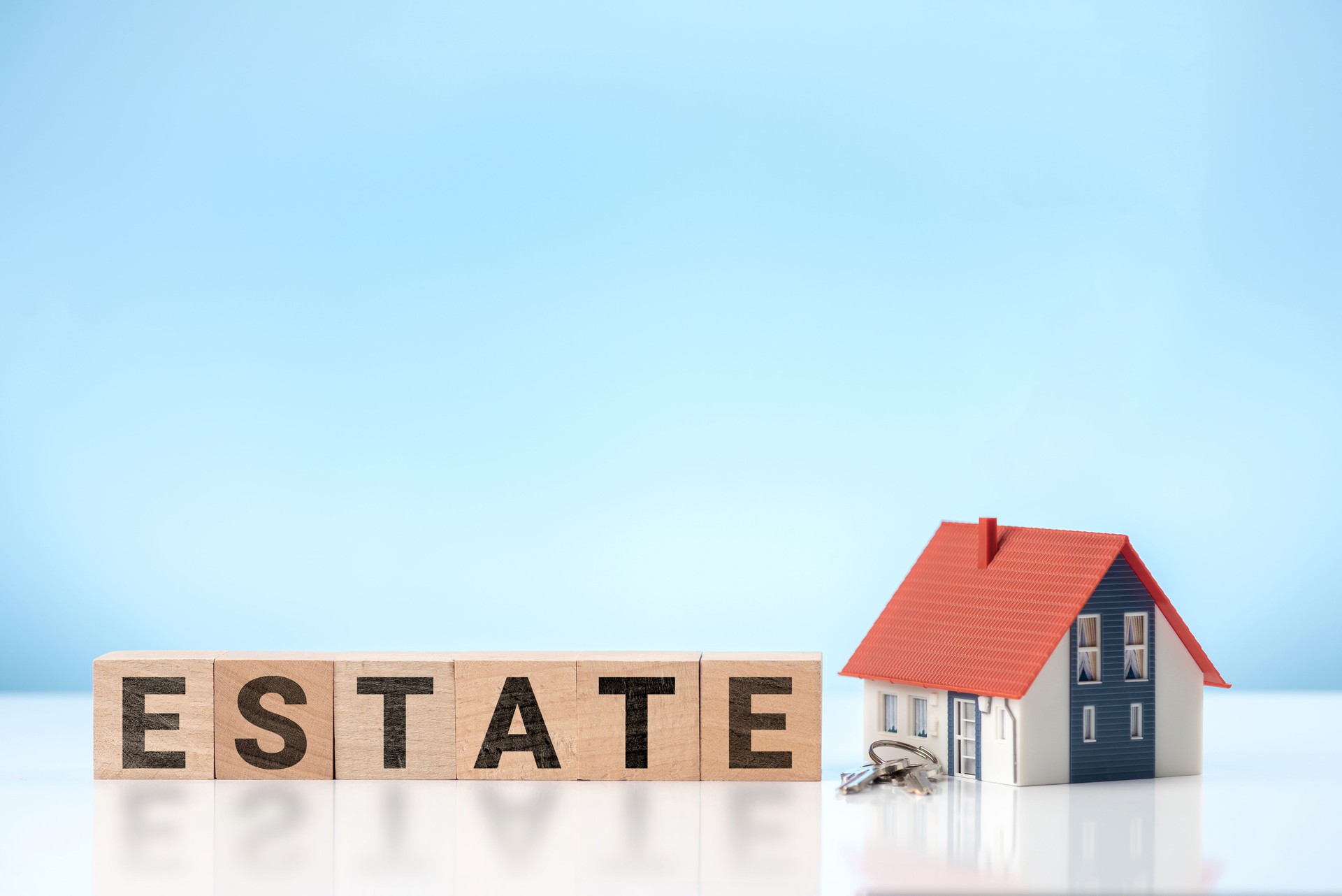 ESTATE word on wooden cube with Model house and house key. Business concept